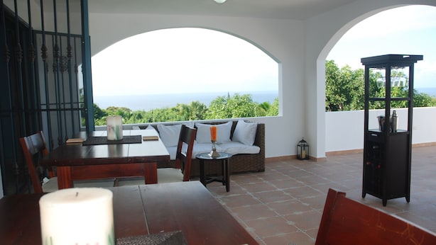 A terrace with a dining table, chairs, a sofa, and a view of the sea. - E&J Boutique Residences (Sosúa)