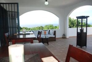 A terrace with a dining table, chairs, a sofa, and a view of the sea. - E&J Boutique Residences (Sosúa)