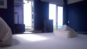 A hotel room with a bed, a small table, a TV, and a window with a view. - E&J Boutique Residences (Sosúa)