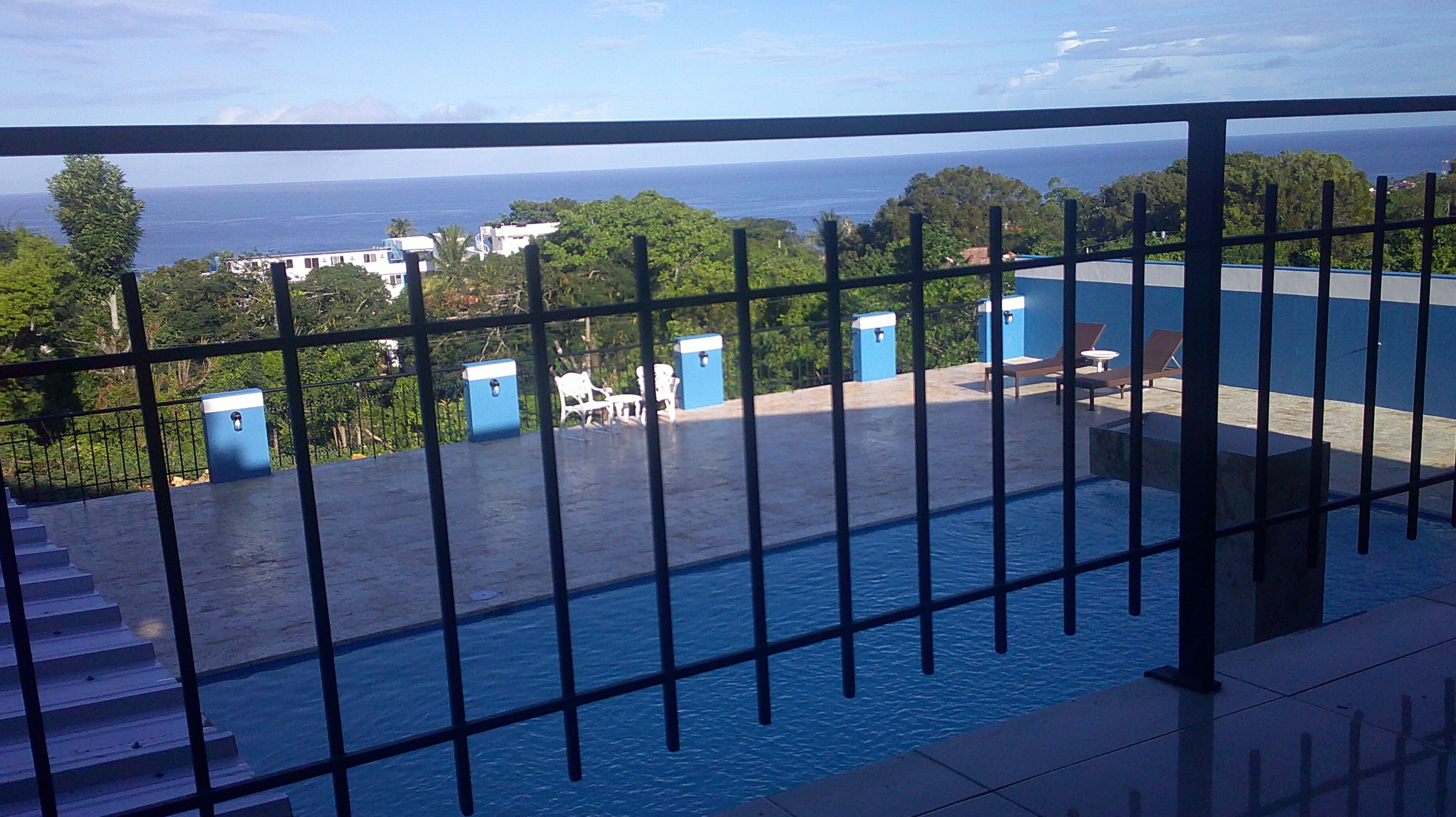 Ein Poolbereich mit Blick auf das Meer und Gebäude in der Ferne.