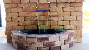 A brick wall with a circular water feature in the center. - Executive Inn and Suites (Goliad)