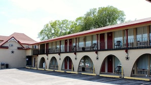 A motel with a central courtyard, multiple balconies, and arched doorways. - Executive Inn and Suites (Goliad)
