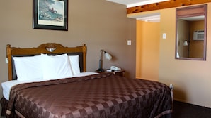 A hotel room with a large bed, a nightstand, a framed picture on the wall, and a mirror. - Executive Inn and Suites (Goliad)