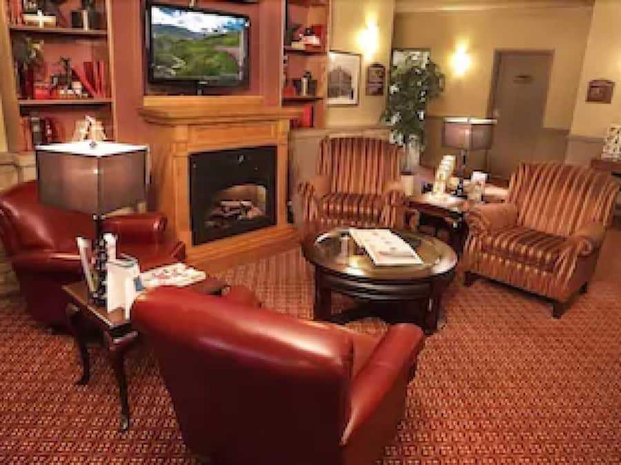 Un vestíbulo de hotel con sofás de cuero, una chimenea, un televisor y una estantería.
