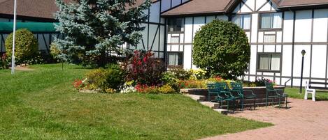 A traditional half-timbered building with a well-maintained lawn, benches, and a flagpole.