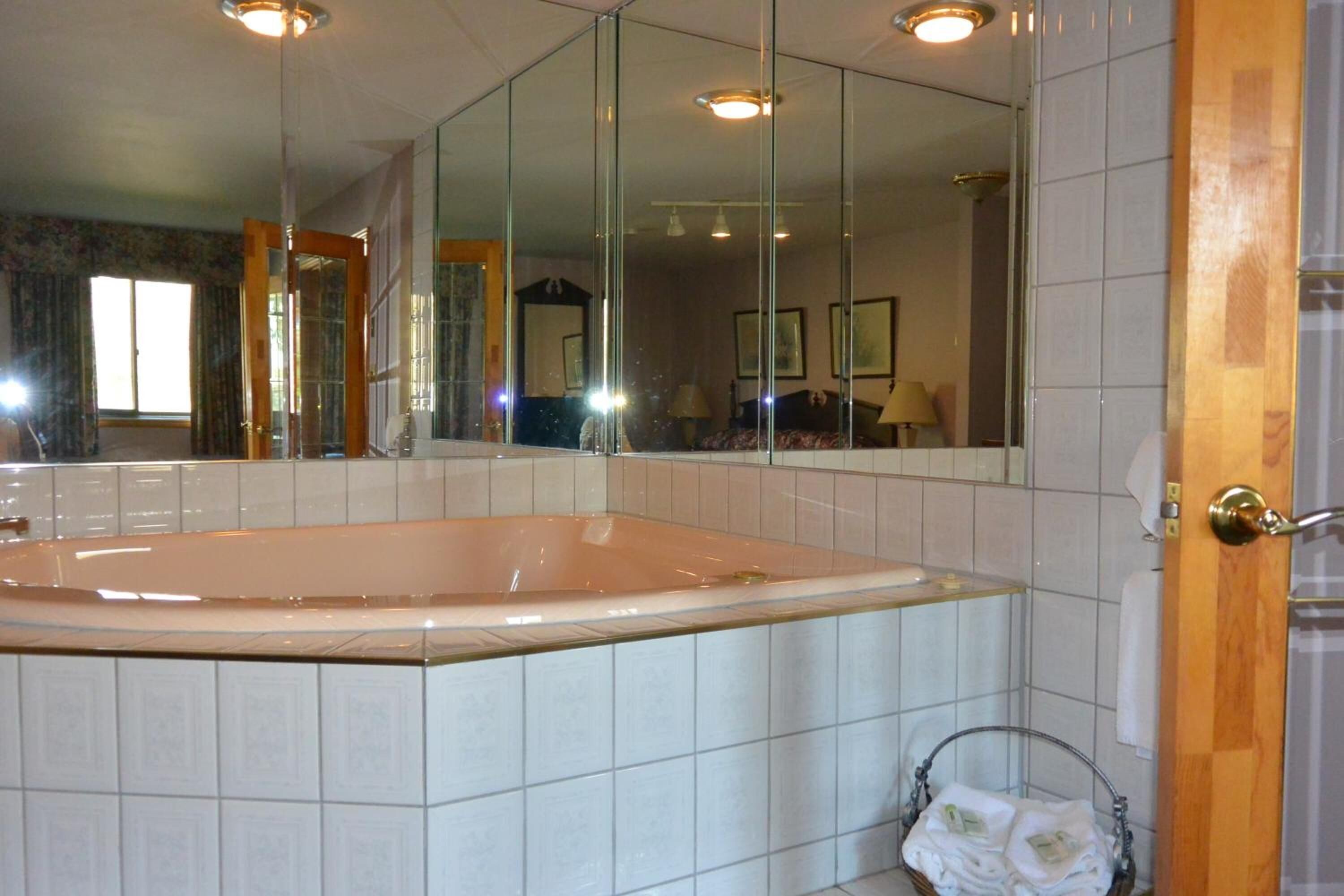 Une salle de bain avec une grande baignoire, un miroir et un porte-serviettes.