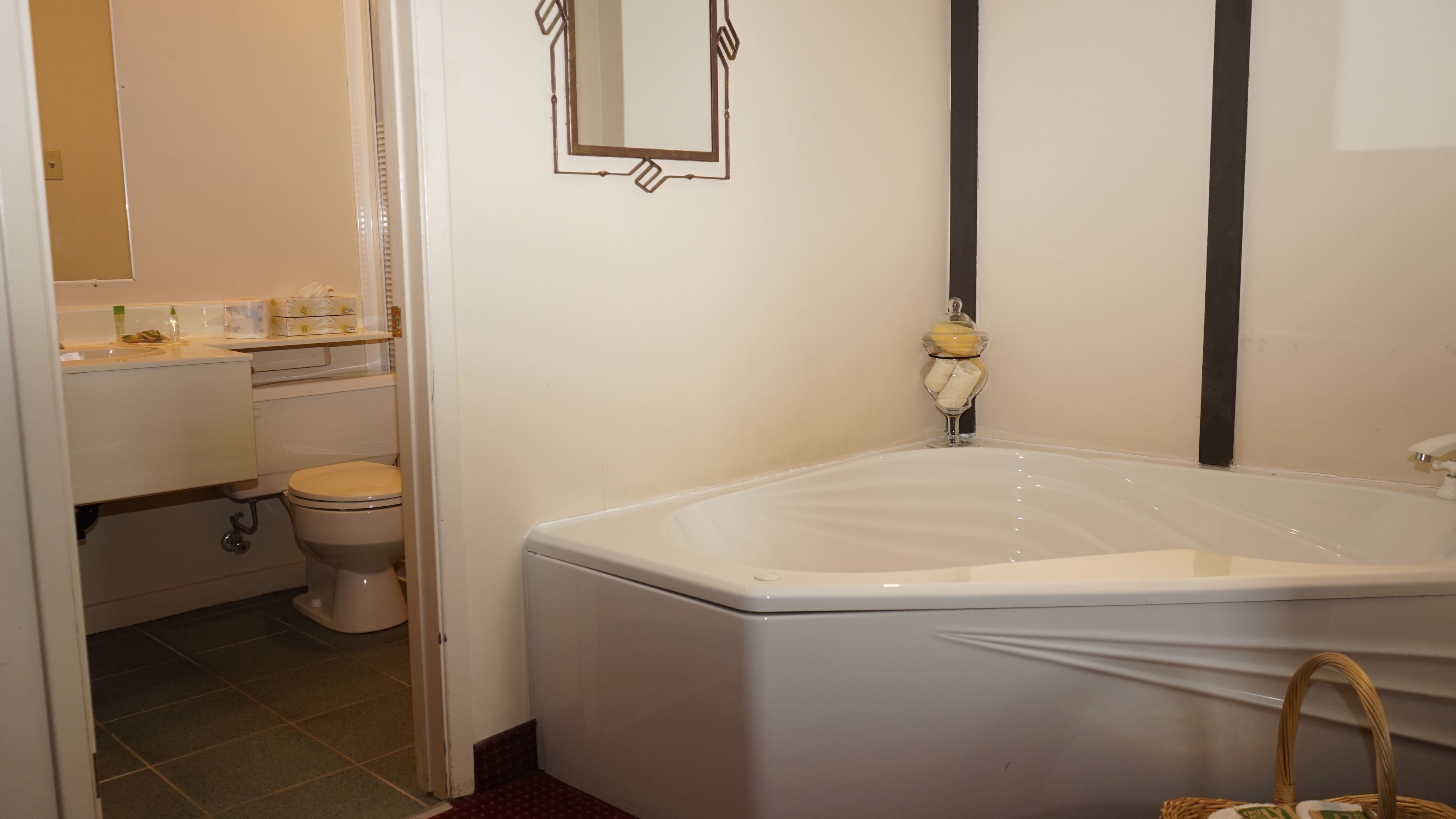 A bathroom with a bathtub, toilet, sink, and a mirror on the wall.