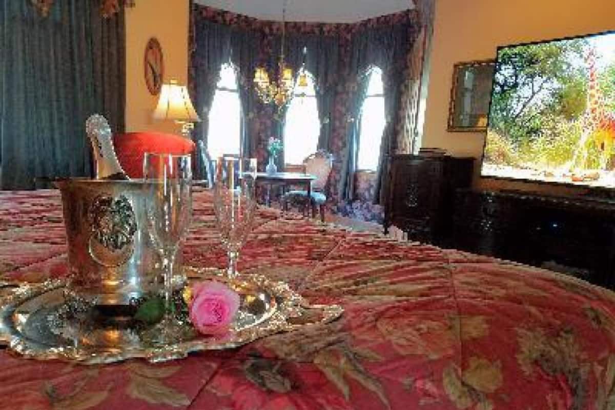 A room with a large bed, a television, and a dining area with a table and chairs.