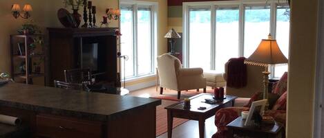 A living room with a fireplace, a dining area, and a seating area with a view of the outdoors.