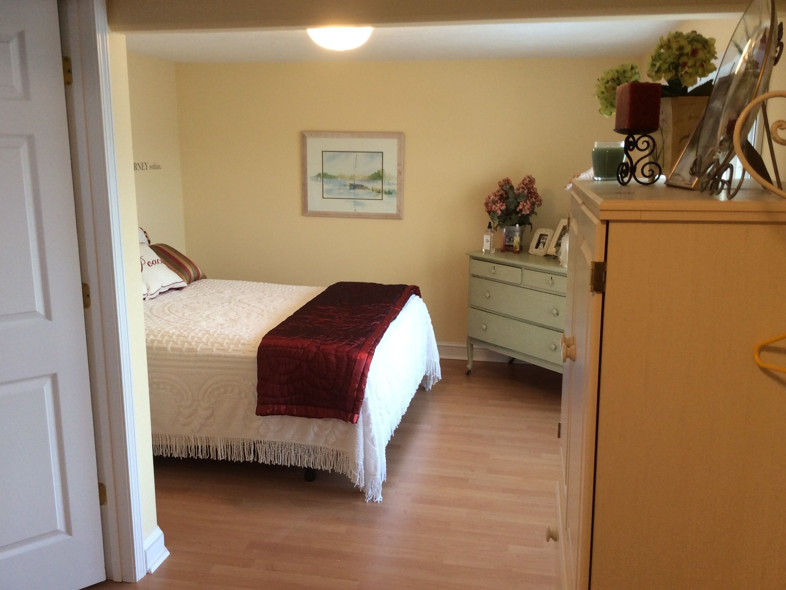 A bedroom with a bed, a dresser, and a painting on the wall.
