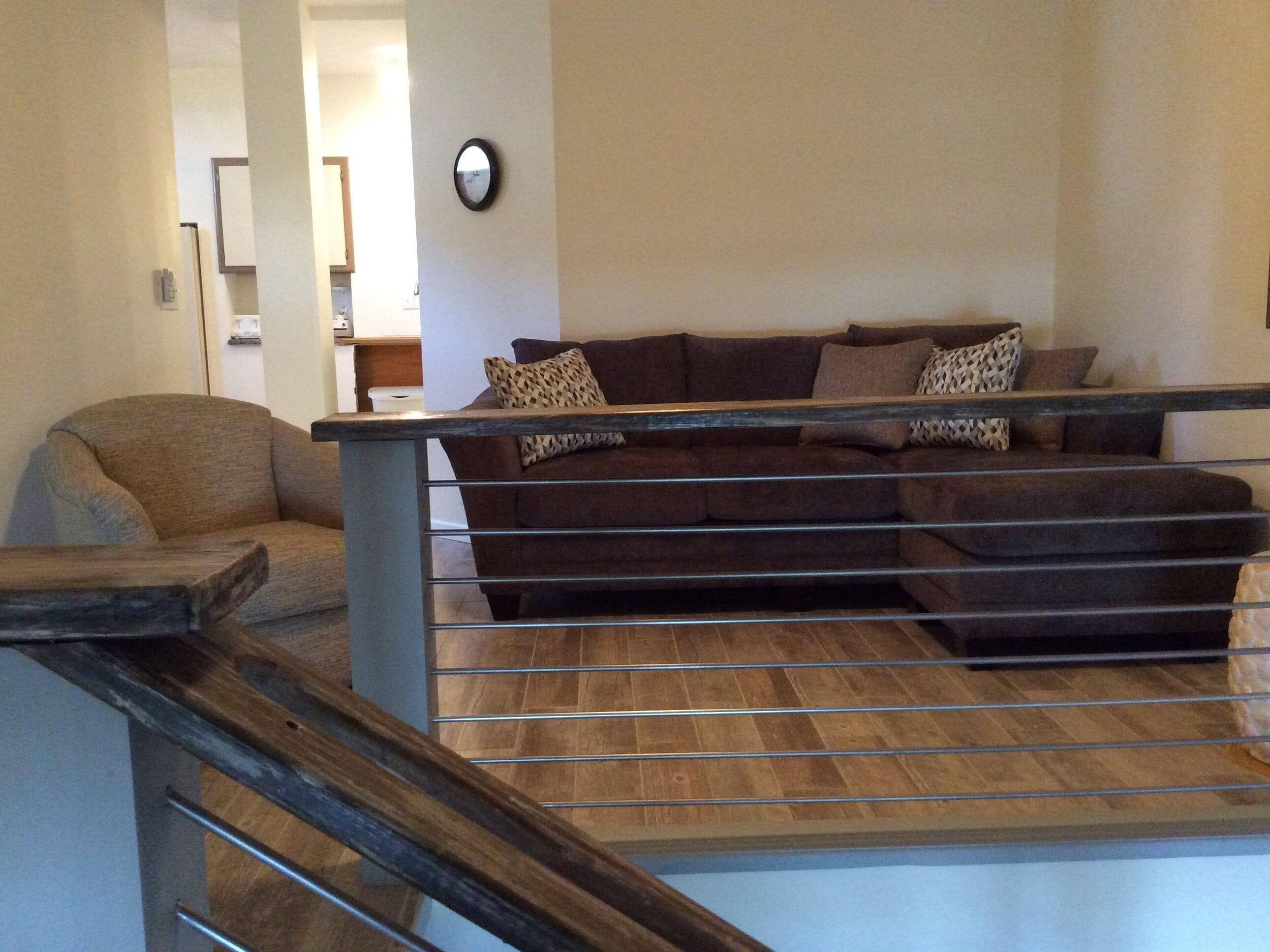 A living room with a brown sofa, a wooden coffee table, and a staircase with a metal railing.