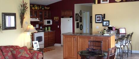 A spacious living room with a sofa, a coffee table, and a dining area with chairs and a glass-top table.