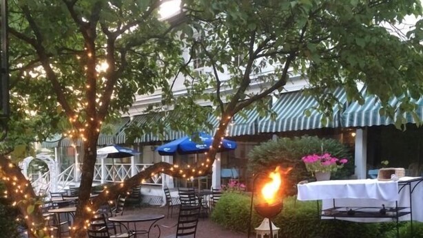 An outdoor seating area with tables and chairs, surrounded by greenery and string lights. - The Brick Hotel (Newtown)