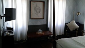 A hotel room with a bed, a desk with a chair, a television, and a framed artwork on the wall. - The Brick Hotel (Newtown)