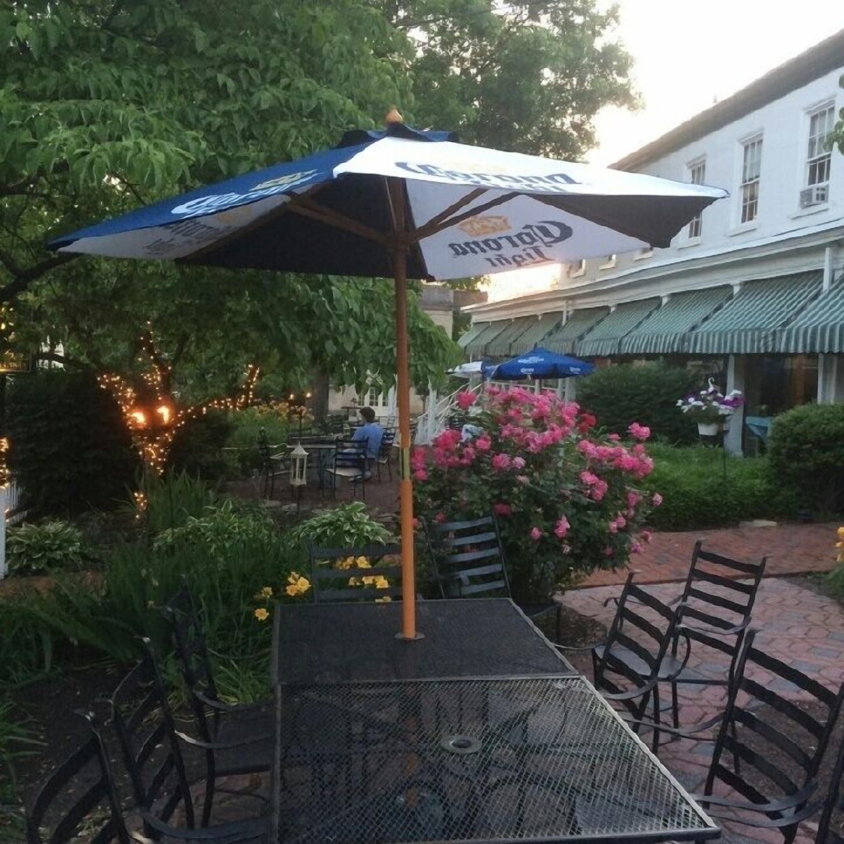An outdoor seating area with tables and chairs, a decorative umbrella, and a flower arrangement.