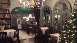 A dining area with tables and chairs, a chandelier, and a Christmas tree. - The Brick Hotel (Newtown)
