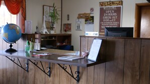 Una recepción con detalles de madera, un globo terráqueo, un cartel de bienvenida y un letrero de prohibido fumar.