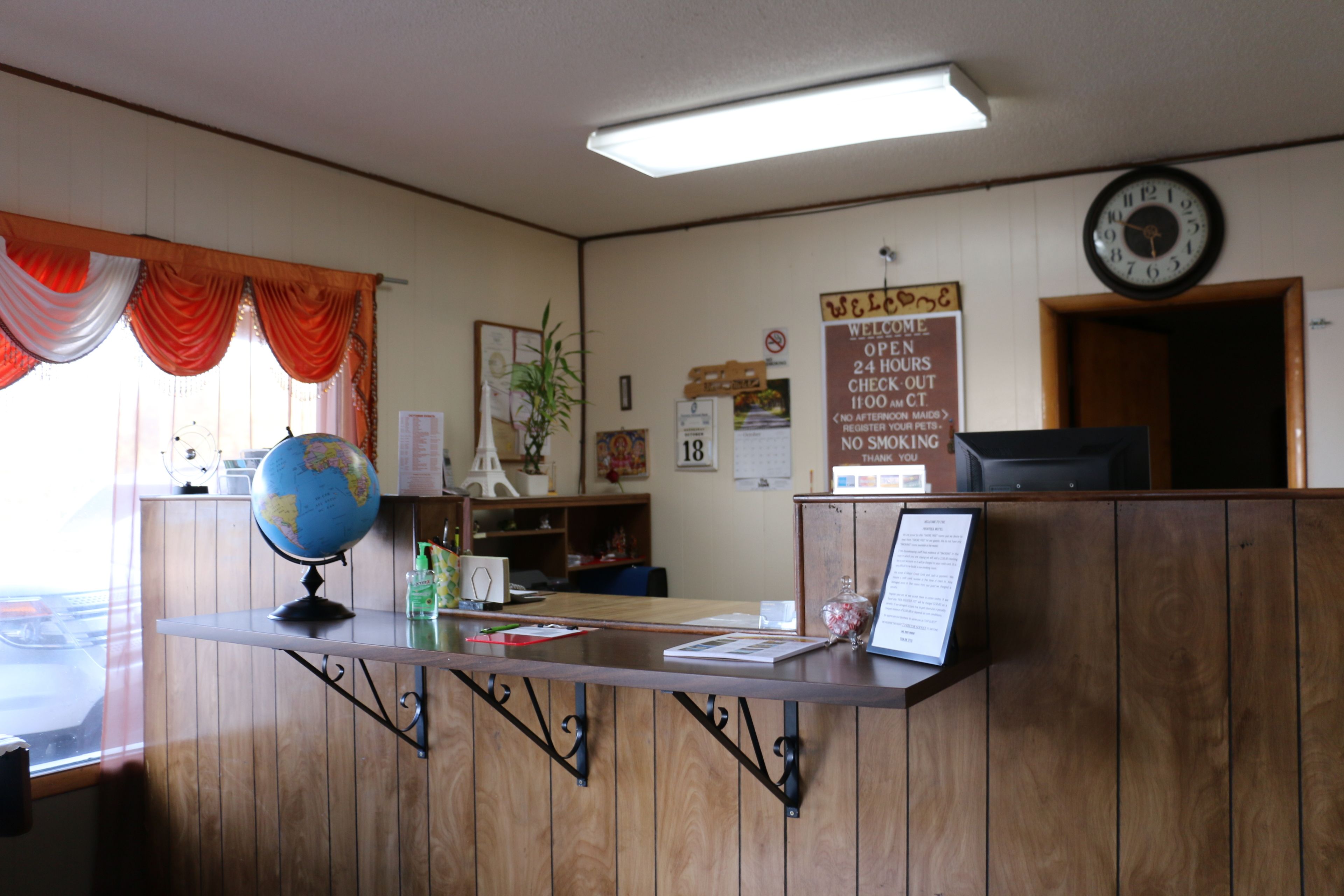 A reception desk with a wooden finish, a globe, and a clock on the wall.