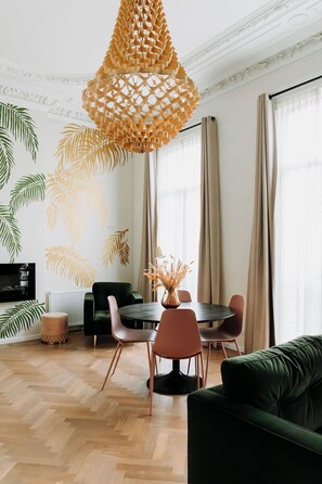 A modern living room with a round dining table, a sofa, and a unique woven light fixture. - La Paulowna Boutique Hotel (The Hague)