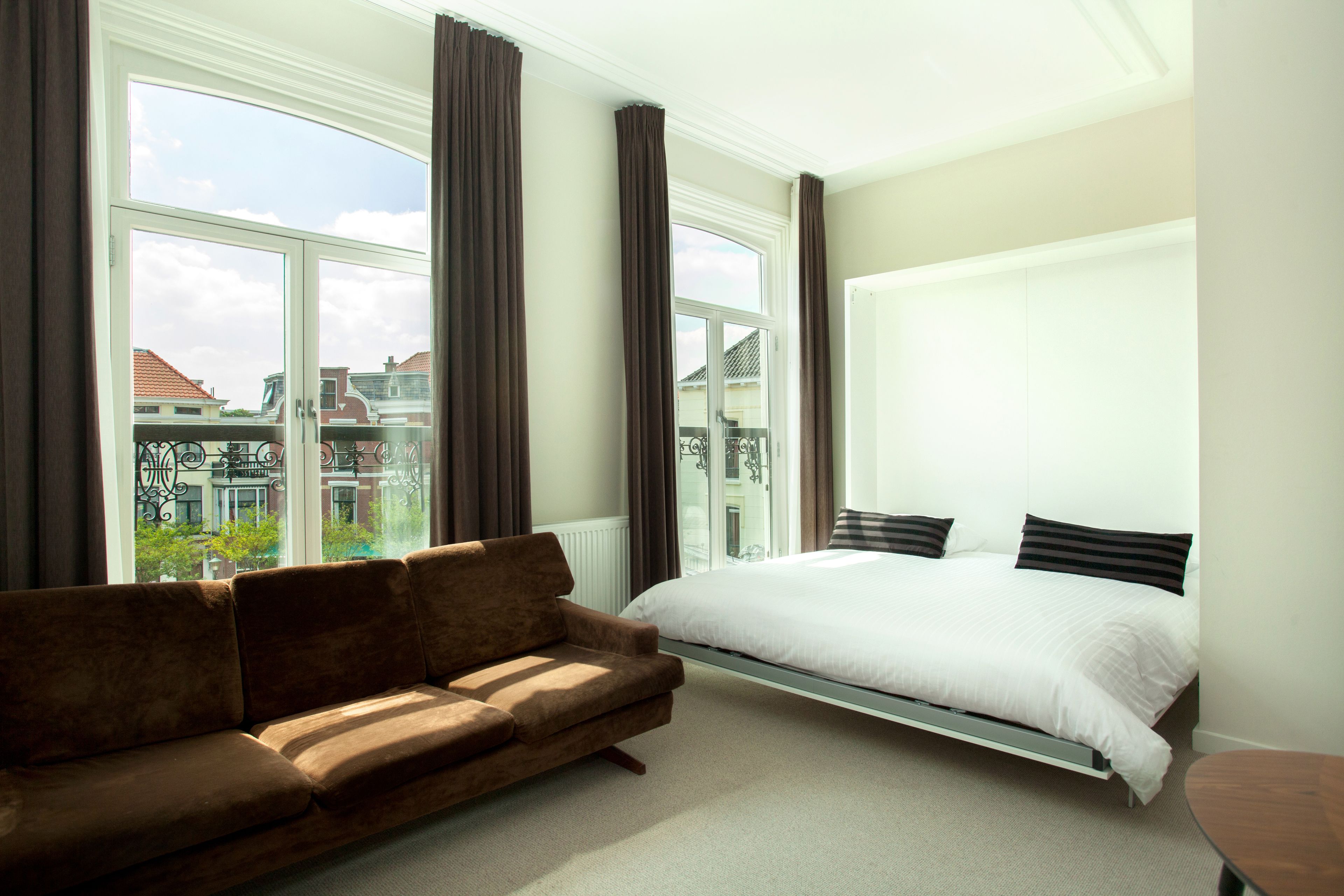 Un dormitorio con cama, sofá y ventanas amplias.