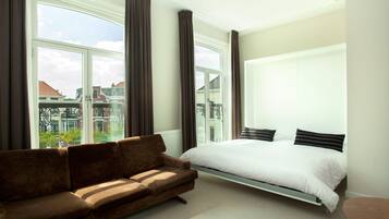 Un dormitorio con cama, sofá y ventanas amplias.