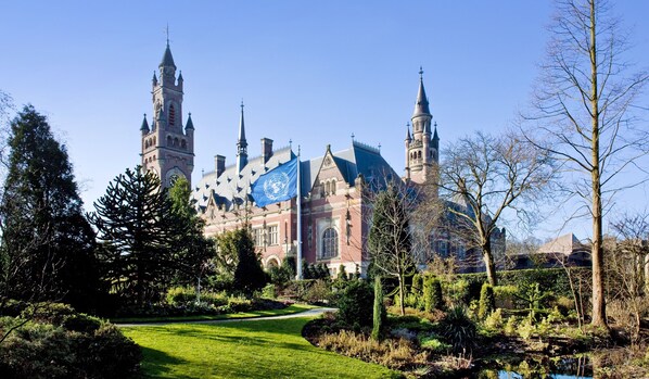 A historic building with multiple towers and a flagpole with a blue flag.