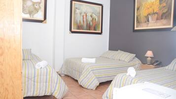 Habitación de hotel con dos camas, ropa de cama a rayas, una mesita de noche con lámpara y obras de arte enmarcadas en las paredes.
