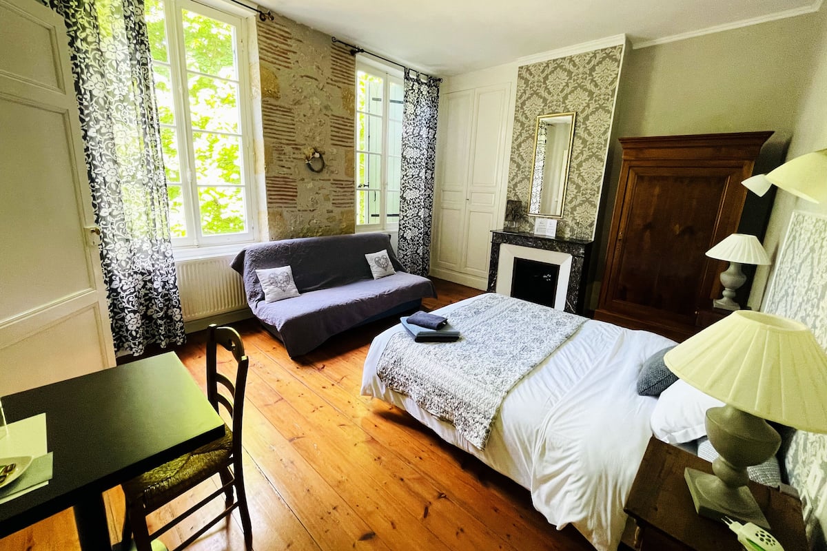 Un dormitorio con cama, sofá, mesa y chimenea.