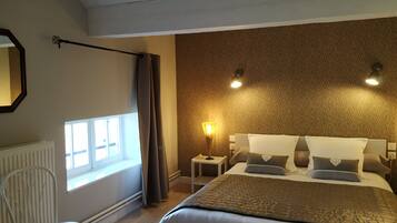 Un dormitorio con una cama, una mesita de noche, una lámpara, una silla y una ventana.
