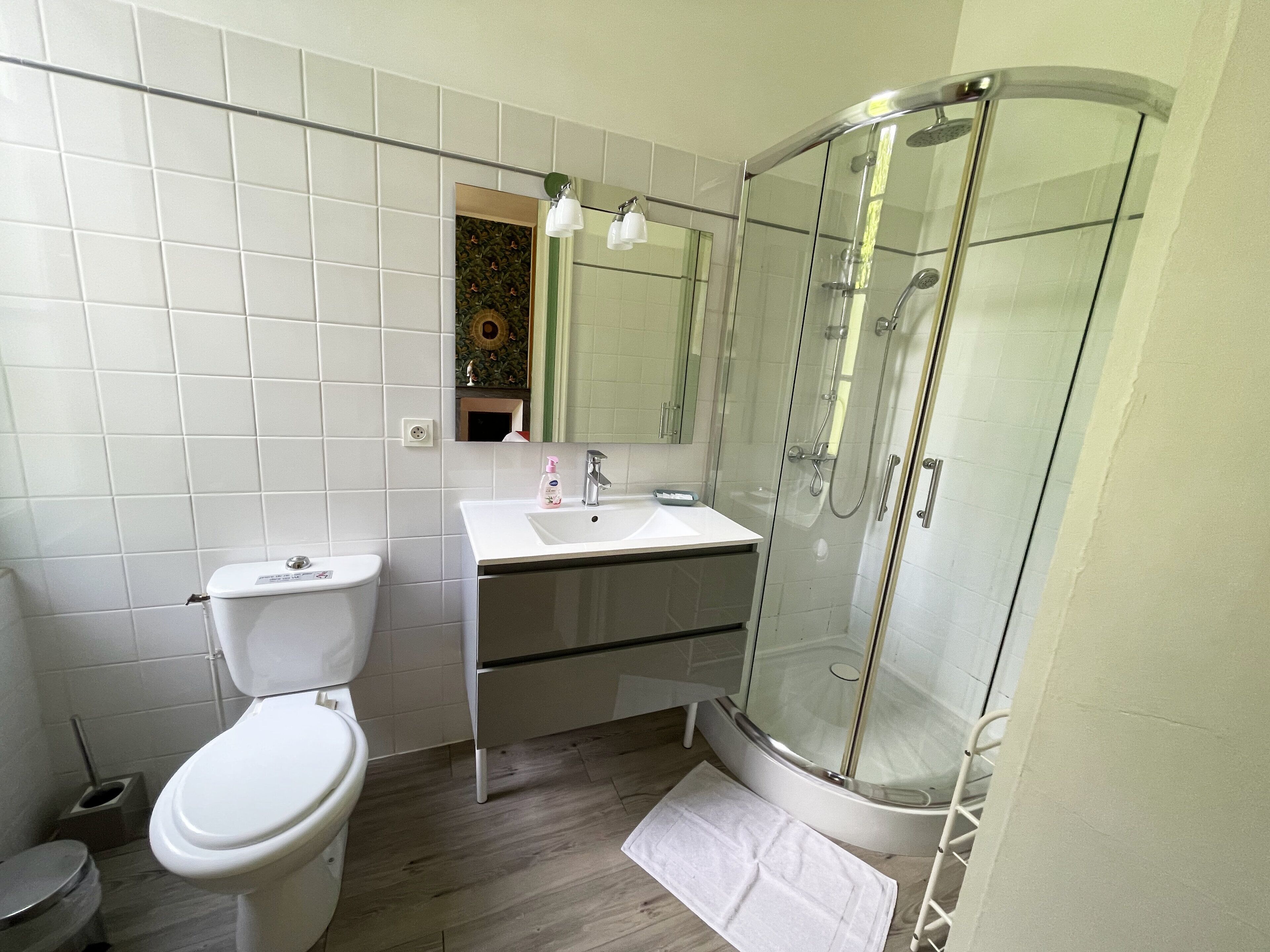 Une salle de bain moderne équipée de toilettes, d’un lavabo et d’une douche à parois de verre.