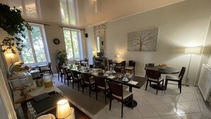 Un comedor bien iluminado con varias mesas y sillas, una chimenea y un amplio ventanal que proporciona luz natural.
