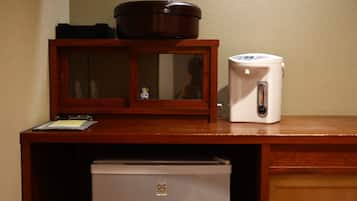 A wooden desk with a microwave, a small refrigerator, and a cabinet with a glass door.