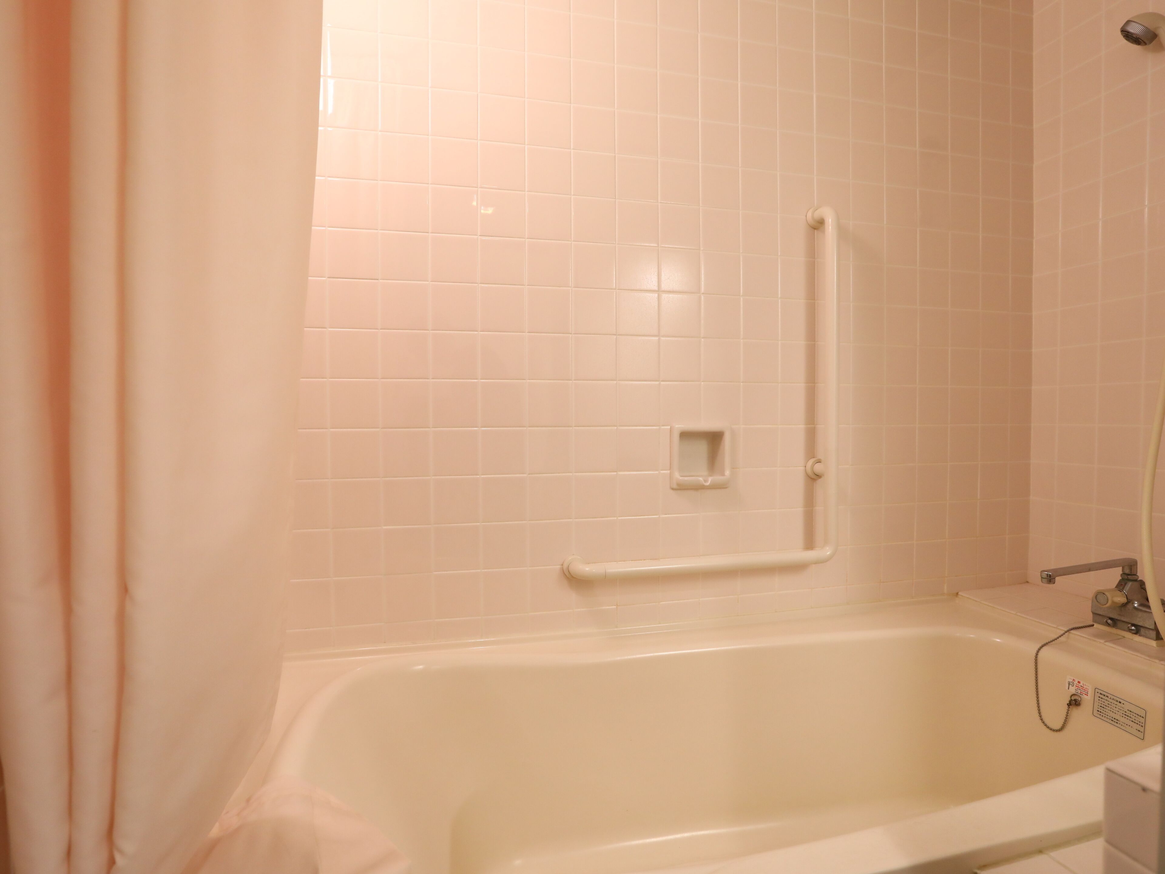 A bathroom with a bathtub, a shower area, and a handrail.