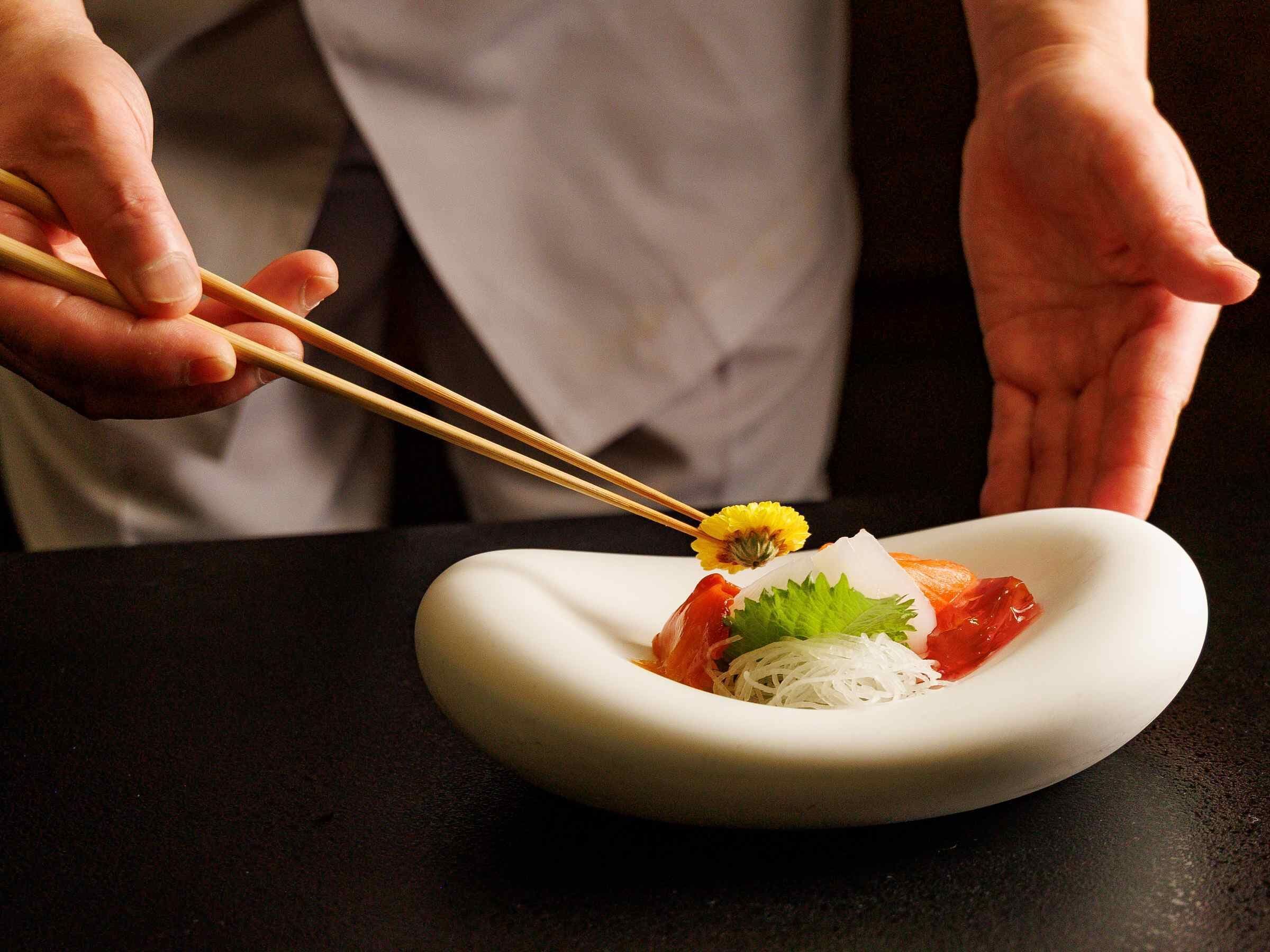 A person holding chopsticks over a plate of food.