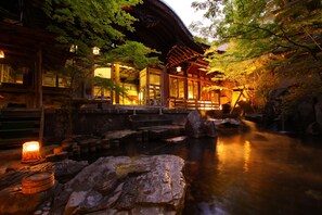 Un edificio japonés tradicional con un estanque de carpas y un farol de piedra.