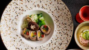 A plate with food, a bowl of soup, and chopsticks on a table.
