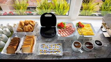 Un bufé de desayuno con diferentes opciones de comida y una máquina para hacer gofres.