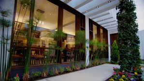A modern building with large windows, indoor plants, and a well-maintained garden.