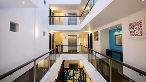 A multi-level interior with glass railings, an elevator, and a staircase with a decorative art piece.