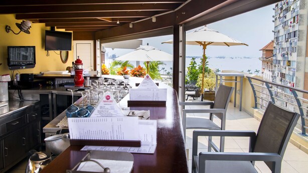A bar area with a view of the sea, a television, and a fire hydrant. - Hotel Continental (Luanda)