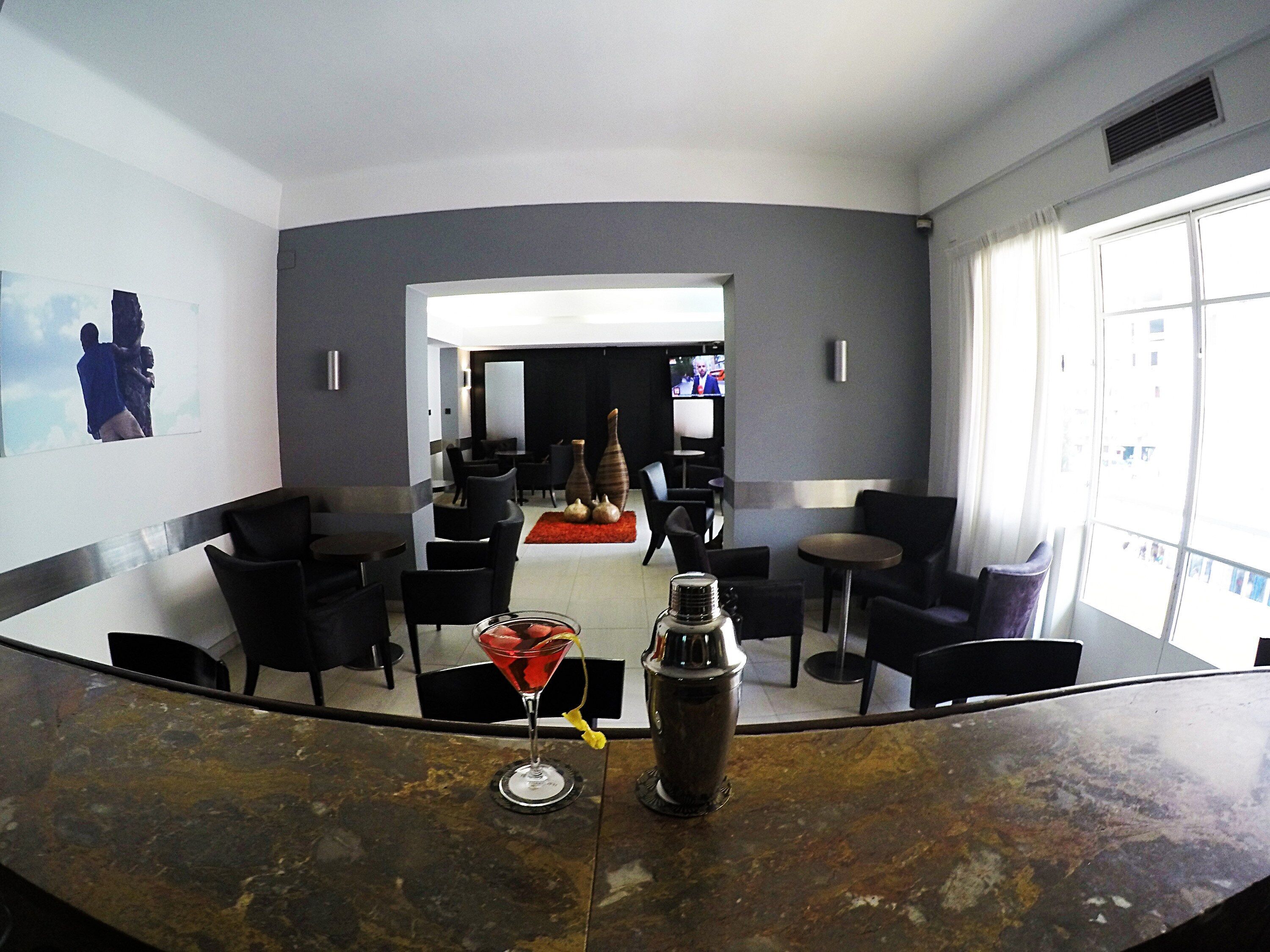 Una zona de bar con una copa de martini y un coctelero sobre la barra.
