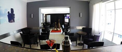 Una zona de bar con una copa de martini y un coctelero sobre la barra.