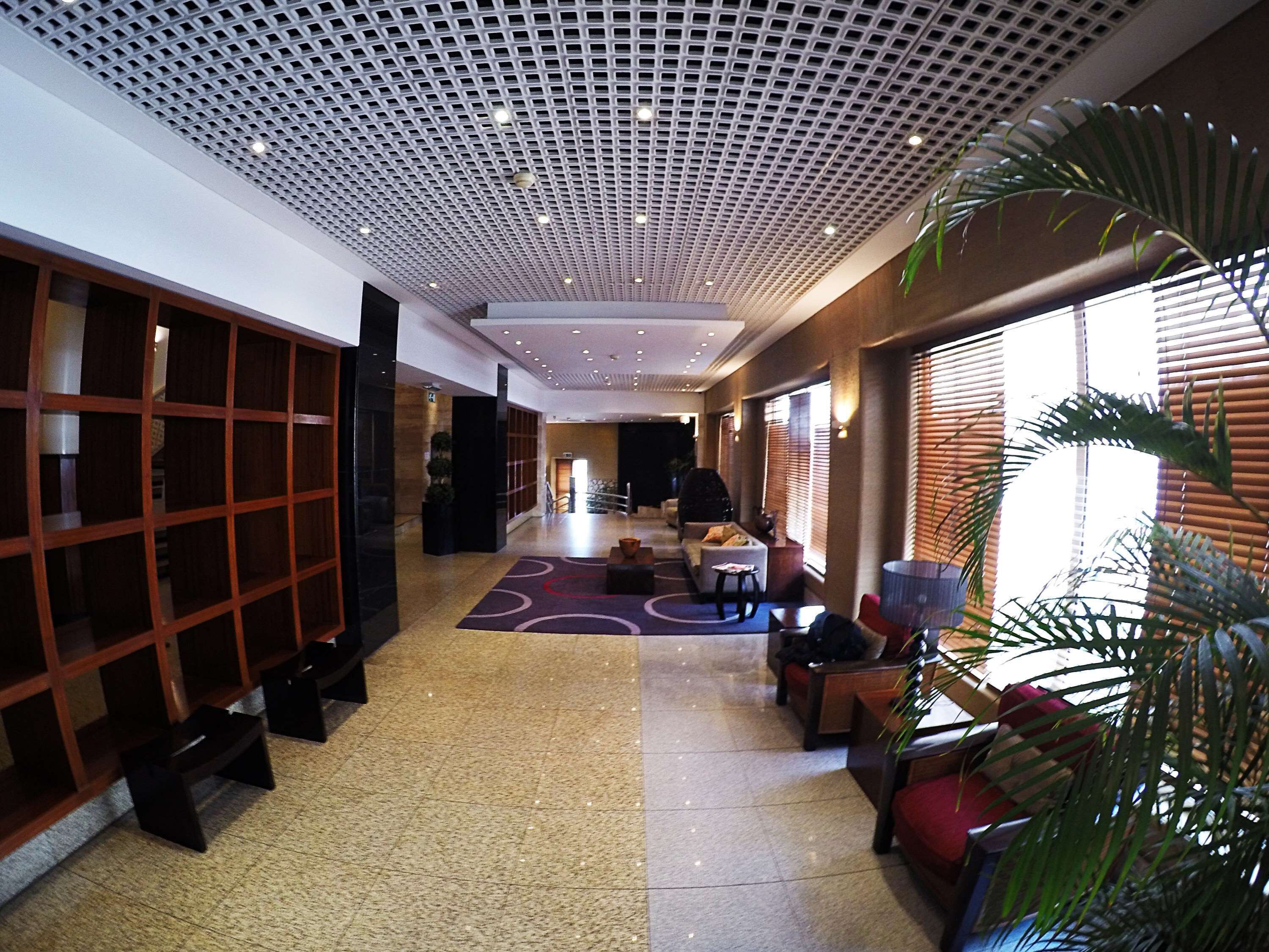 A spacious lobby with a high ceiling, a central seating area, and a large window on the right.