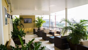 A spacious indoor area with multiple seating arrangements, including sofas and chairs, surrounded by potted plants. - Hotel Continental (Luanda)
