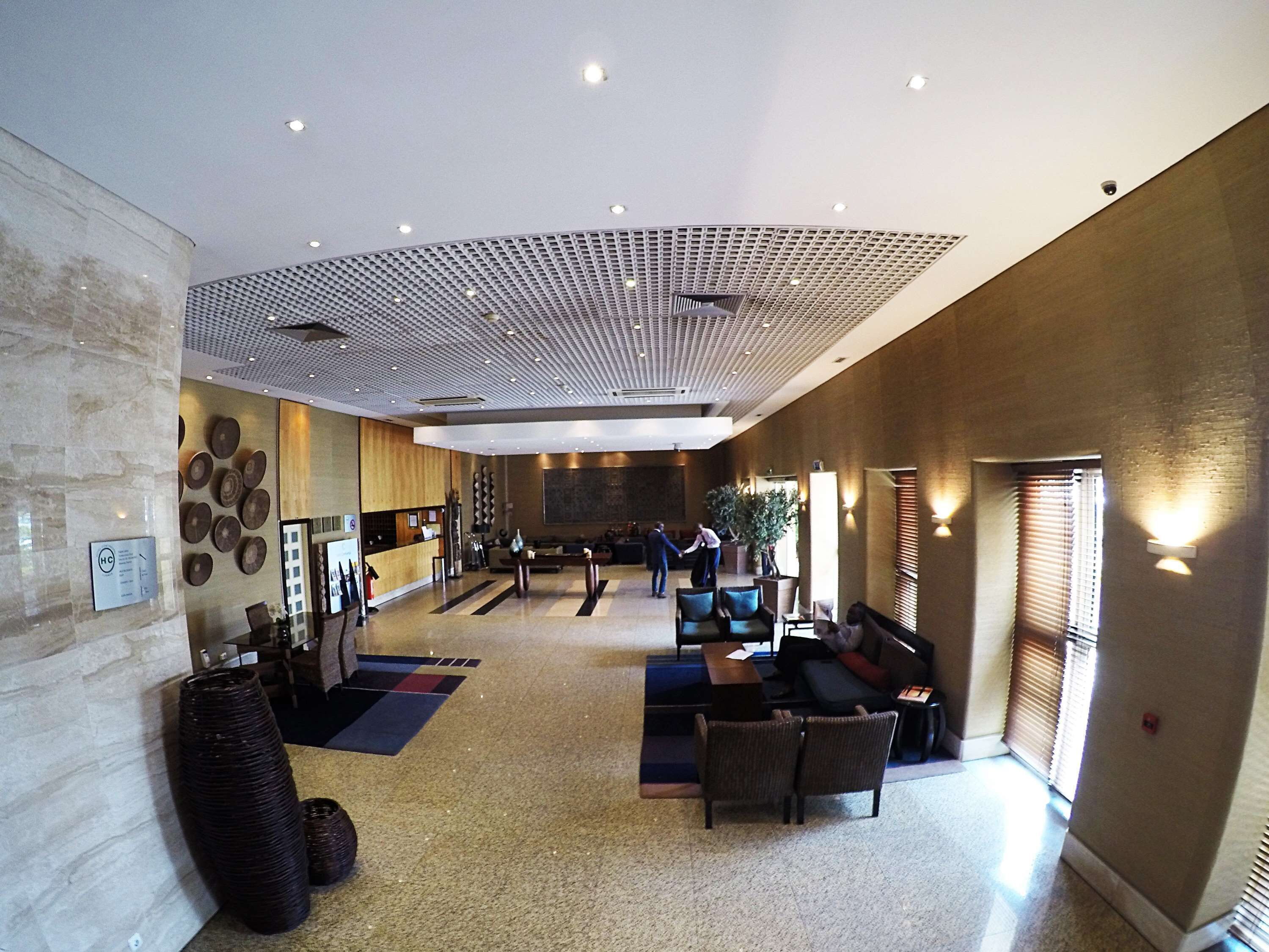 A spacious lobby with a reception desk, seating area, and a high ceiling with a grid pattern.