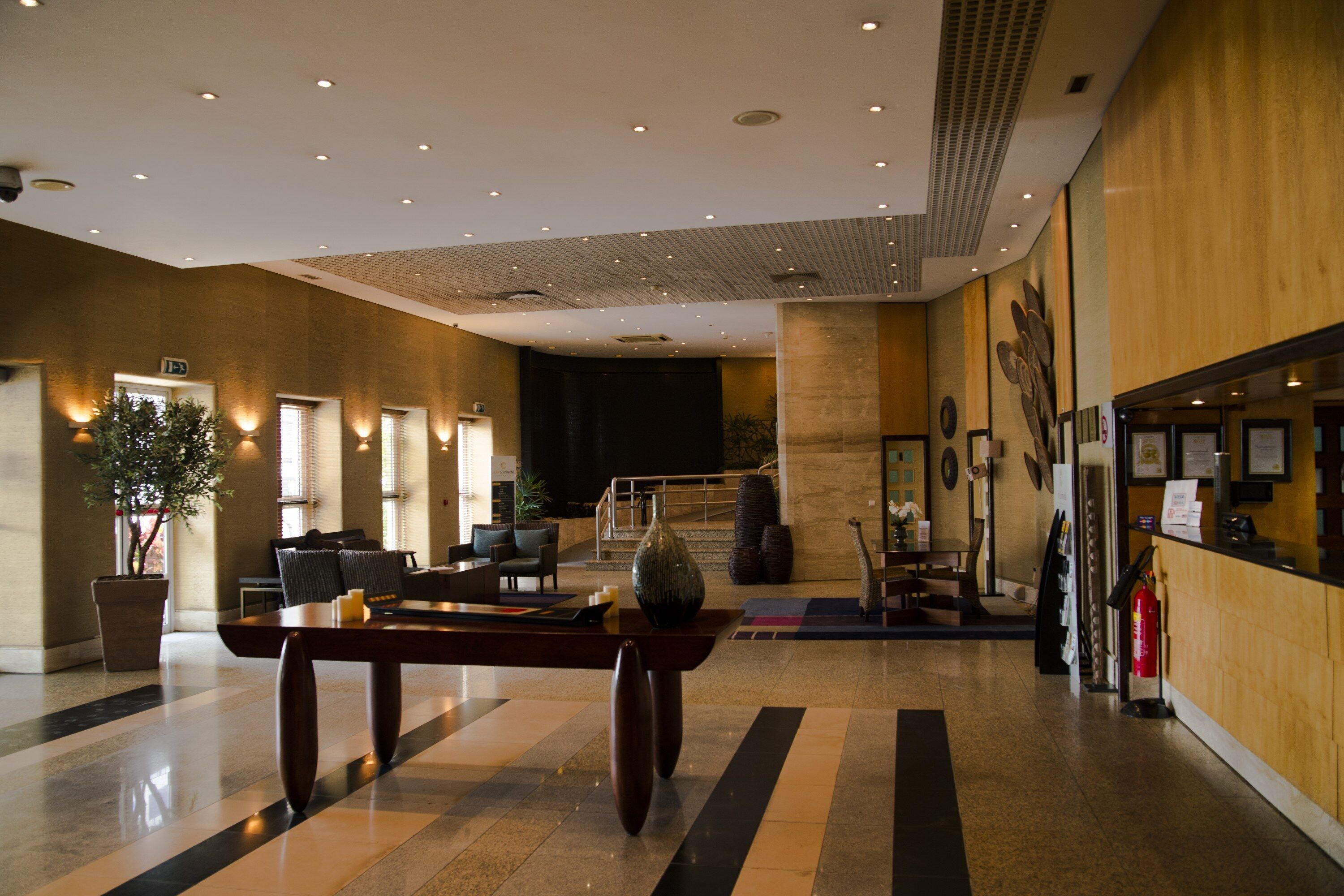 En rummelig lobby med reception, siddeområde og trappe til øvre etager.