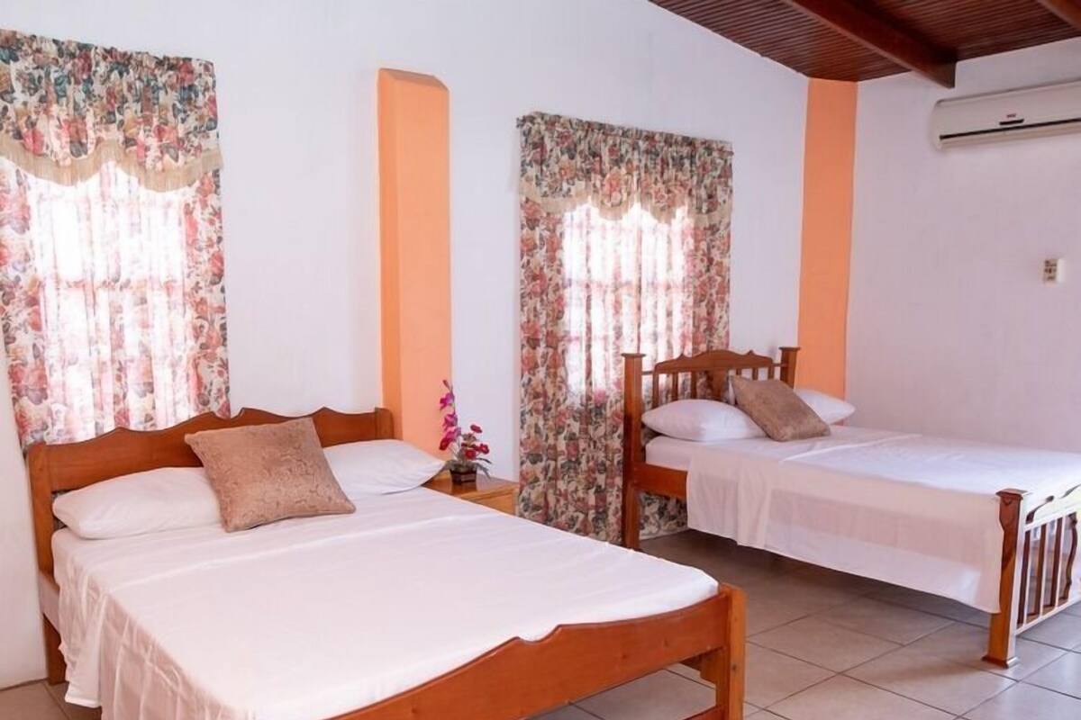 A room with two wooden beds, one larger and one smaller, with white bedding.