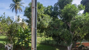 A two-story building with a balcony, air conditioning units, and a small garden area.