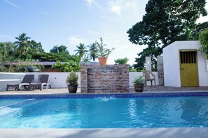 A swimming pool with a tiled edge, lounge chairs, and potted plants. - Lesville Tobago (Canaan)