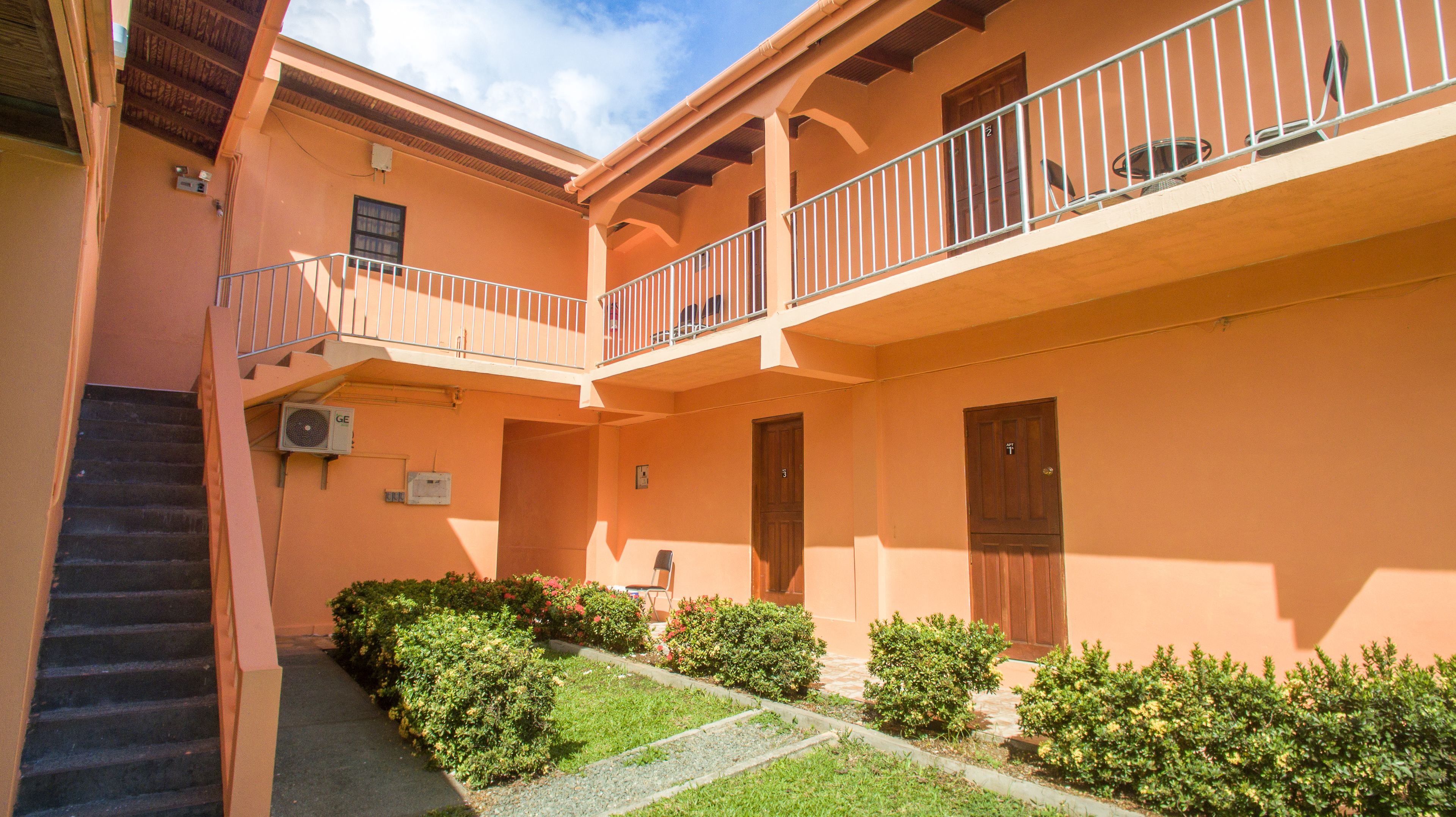 Ein Gebäude mit Innenhof, Treppe und einem Balkon mit Geländern.